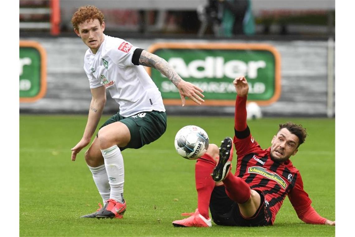 Josh Sargent von Bremen und Manuel Gulde von Freiburg (l-r.) im Zweikampf um den Ball. Foto: Thomas Kienzle/AFP-Pool/dpa