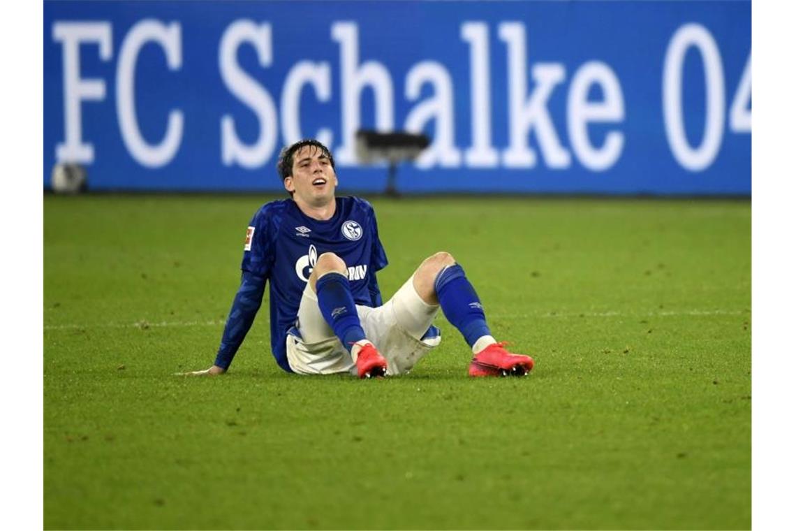 Juan Miranda vom FC Schalke 04 sitzt nach der Partie enttäuscht auf dem Boden. Foto: Ina Fassbender/AFP/Pool/dpa