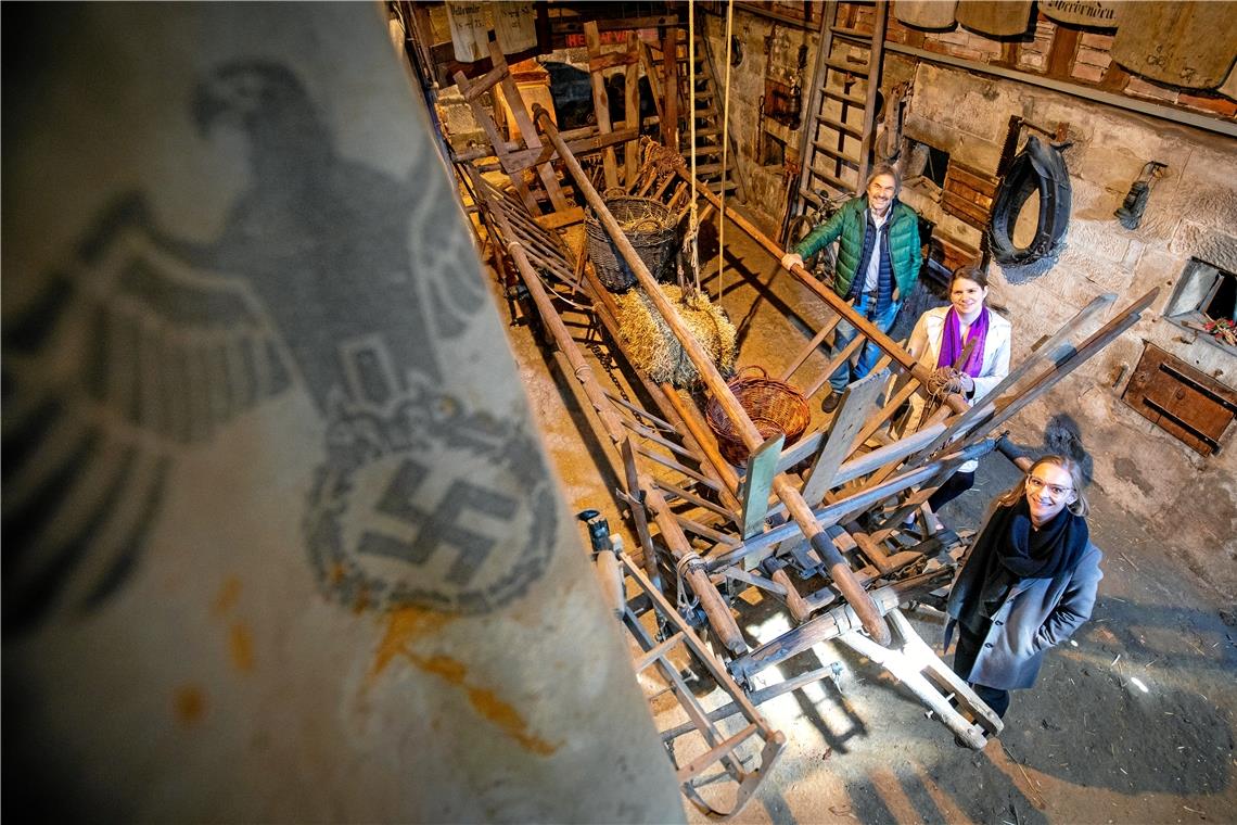 Jürgen Hestler, Carolin Hestler und Roxanne Adler (von links nach rechts) stehen in der Scheune des Heimatmuseums Weissacher Tal. Im Vordergrund hängt der Getreidesack mit dem Hakenkreuz (ein Ausstellungsstück), der den Anstoß zu dem Projekt „Unterweissach im Gleichschritt“ gab. Fotos: A. Becher