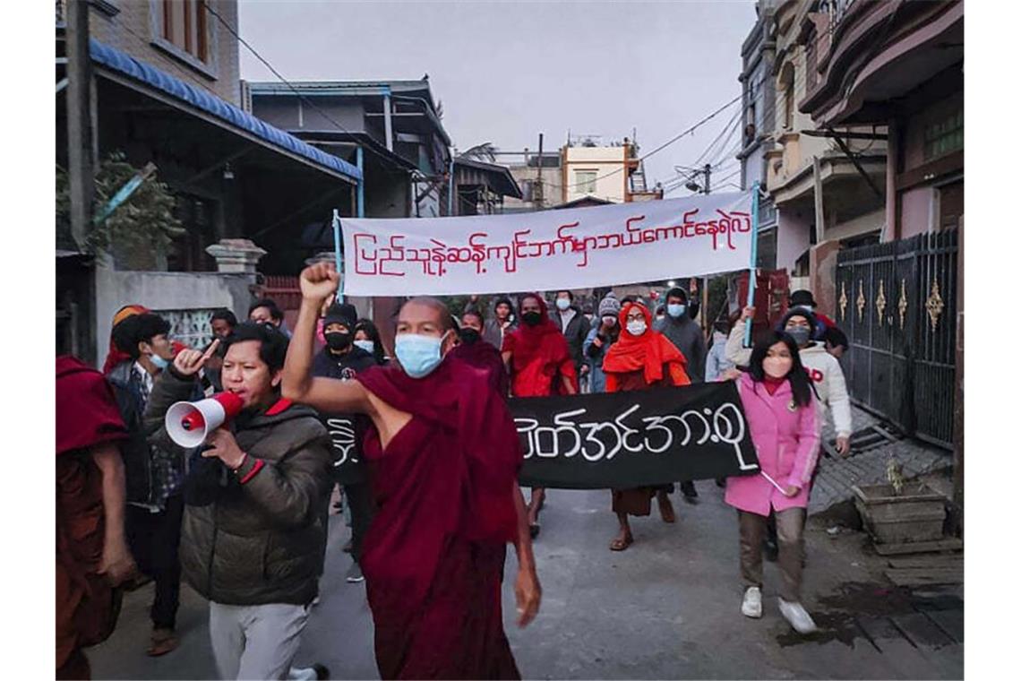 Bittere Bilanz am Jahrestag des Myanmar-Putsches Junge Aktivisten und buddhistische Mönche bei einer Protestkundgebung gegen die Militärregierung in Mandalay. Auf dem Transparent steht in burmesischer Sprache: „Wer wagt es, auf der anderen Seite des Volkswillens zu stehen.“. Foto: Uncredited/AP Photo/dpa