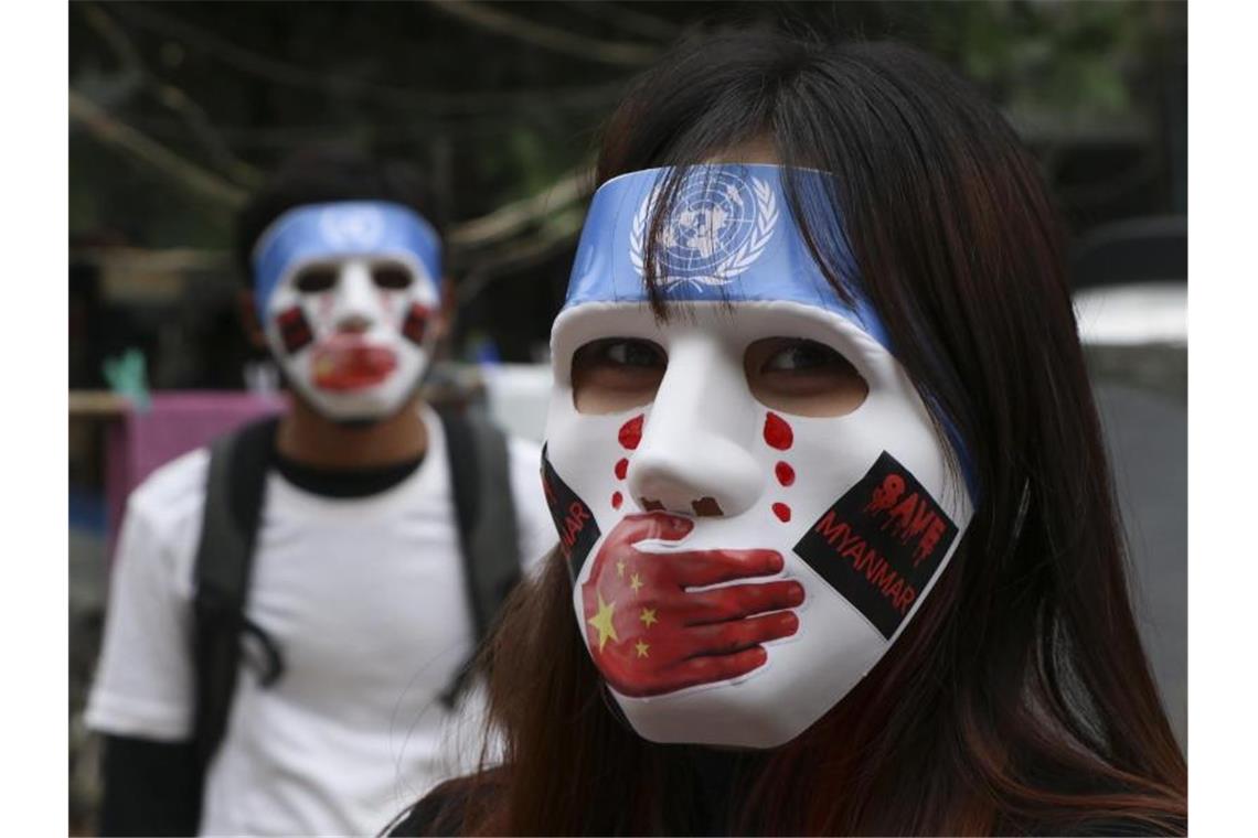 Junge Demonstranten in Yangon tragen Masken, auf denen das Logo der Vereinten Nationen, eine rote Hand über dem Mund, rote Tränen und Aufkleber mit der Aufschrift „Save Myanmar“ zu sehen sind. Foto: Uncredited/AP/dpa