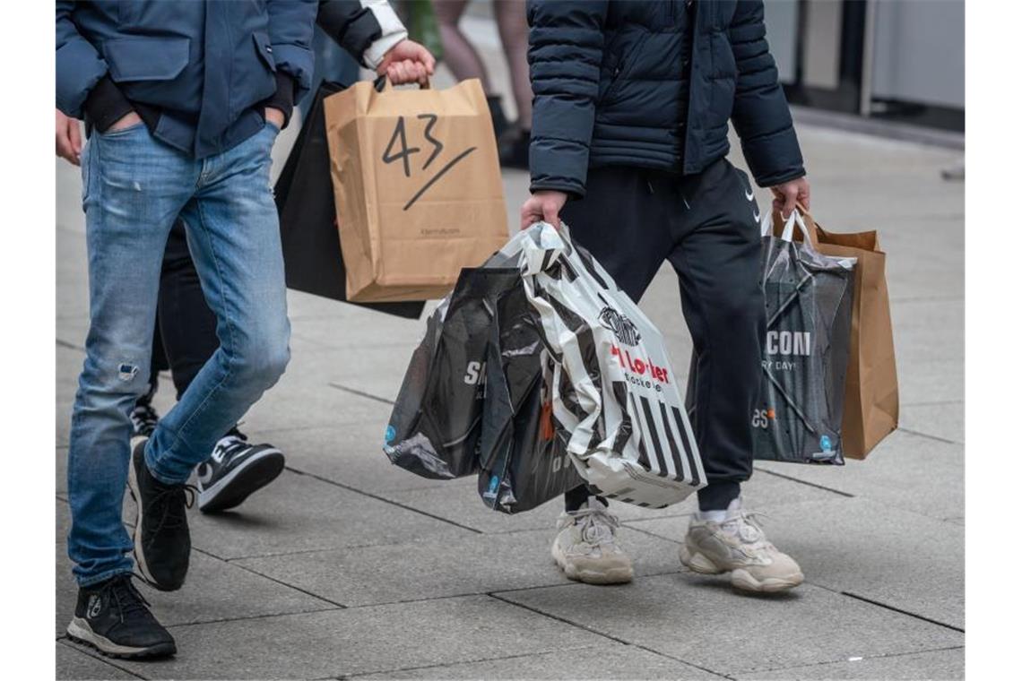 Junge Männer schleppen Einkaufstüten, während auf der Frankfurter Einkausmeile Zeil am Samstag des zweiten Adventswochendes reger Betrieb herrscht. Foto: Frank Rumpenhorst/dpa