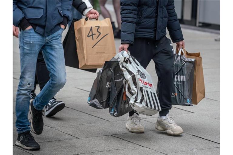 Junge Männer schleppen Einkaufstüten, während auf der Frankfurter Einkausmeile Zeil am Samstag des zweiten Adventswochendes reger Betrieb herrscht. Foto: Frank Rumpenhorst/dpa