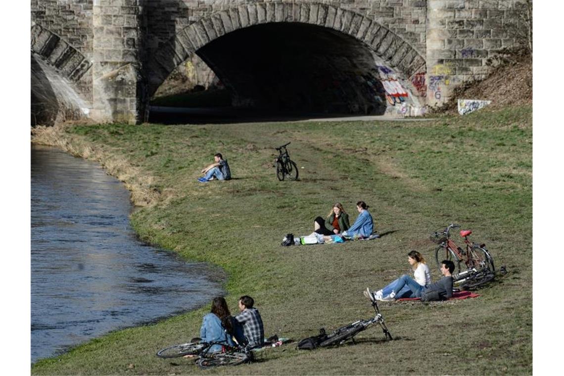 Junge Menschen genießen am Ufer der Leine in Göttingen das milde Wetter. Foto: Swen Pförtner/dpa