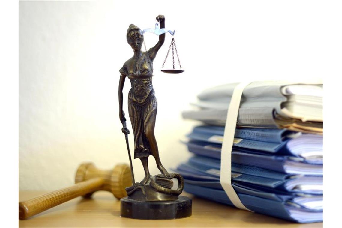 Drei Männer und eine Frau wegen Menschenhandels angeklagt Justitia mit Holzhammer und Aktenstapel. Foto: Volker Hartmann/dpa/Symbolbild