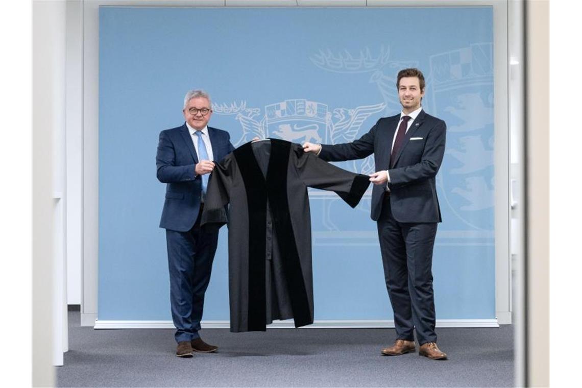 Justizminister Guido Wolf (CDU, l) übergibt eine Robe an Timo Haußer vom Bund Deutscher Rechtspfleger. Foto: Marijan Murat/dpa/Archivbild