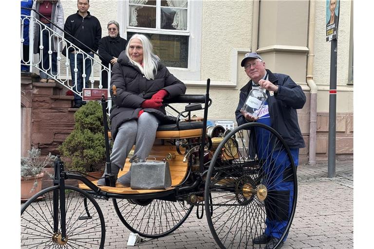 Jutta Benz auf dem Nachbau des Patent-Motorwagens vor der Wieslocher Stadt-Apotheke. Dort hat ihre Urgroßmutter einst einen historischen Tankstopp eingelegt.