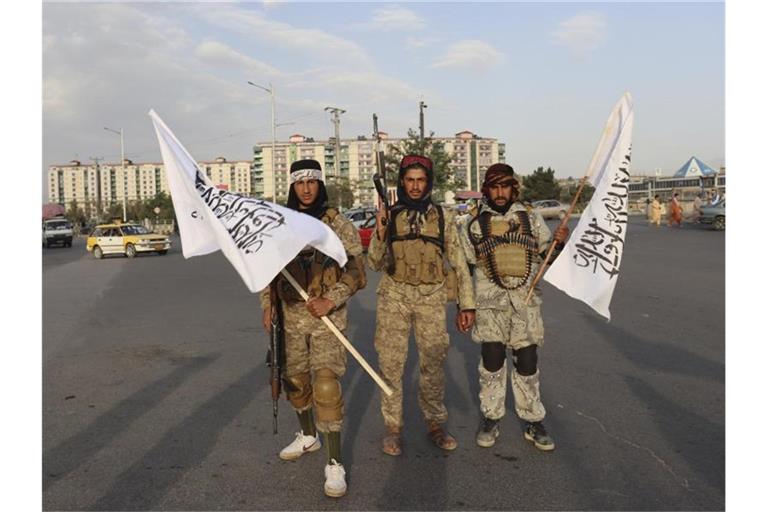 Kämpfer der Taliban stehen mit Flaggen auf einer Straße in der afghanischen Hauptstadt Kabul. Foto: ---/AP/dpa