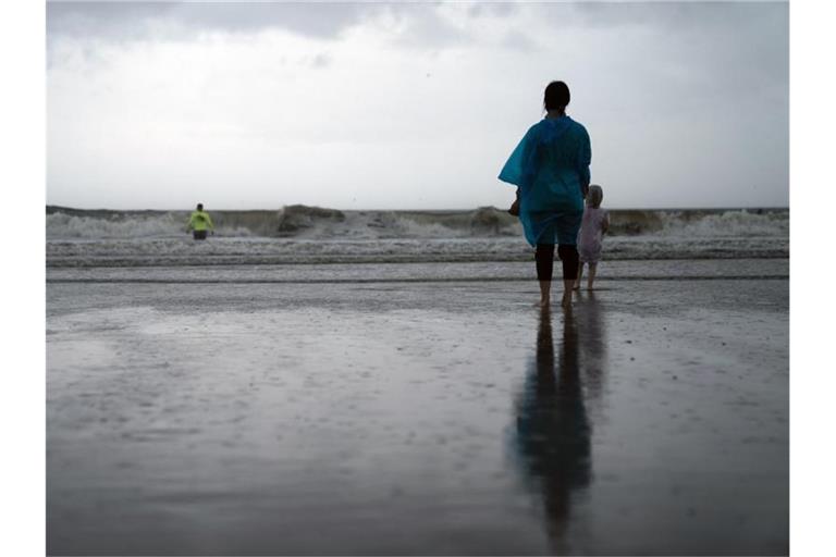 Kamila Struk (r) beobachtet ihren Vater Nickolas, der an einem gesperrten Strand in die Wellen watet, während der Tropensturm „Henri“ über den US-Bundesstaat New York zieht. Foto: John Minchillo/AP/dpa