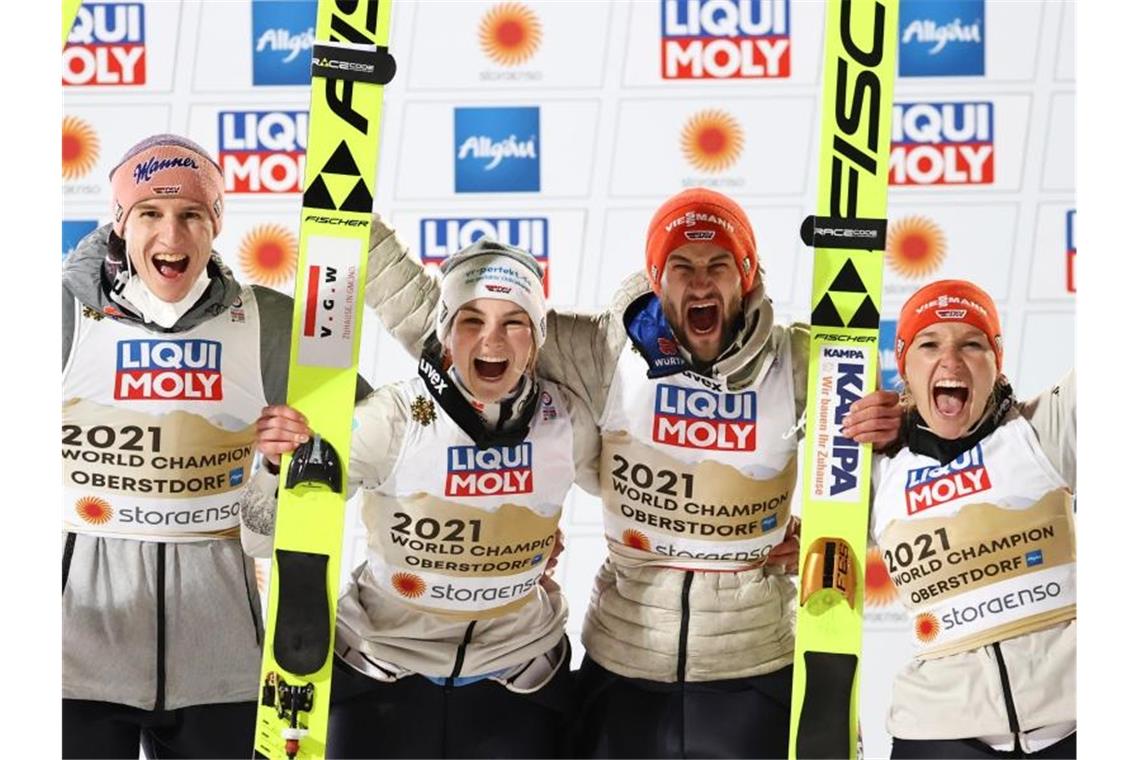 Karl Geiger, Anna Rupprecht, Markus Eisenbichler und Katharina Althaus (l-r) feiern die Goldmedaille bei der Heim-WM in Oberstdorf. Foto: Daniel Karmann/dpa