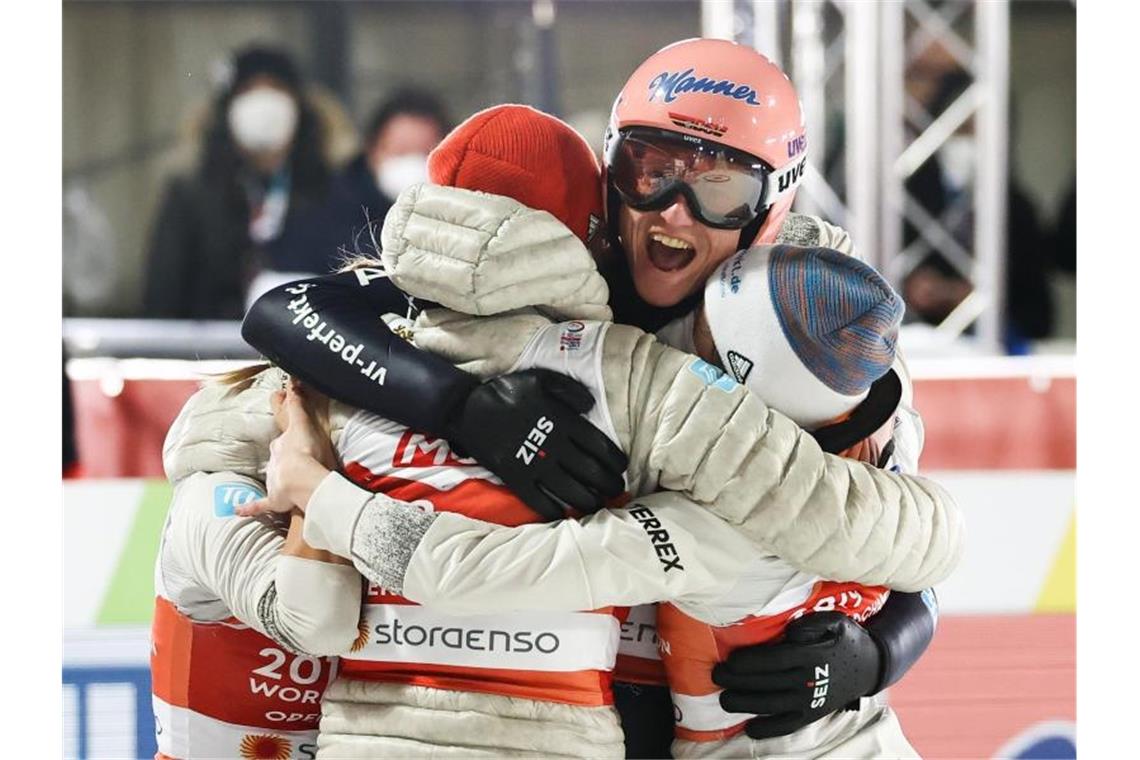 Karl Geiger feiert mit dem Team nach seinem Sprung im letzten Durchgang die Titelverteidigung. Foto: Daniel Karmann/dpa