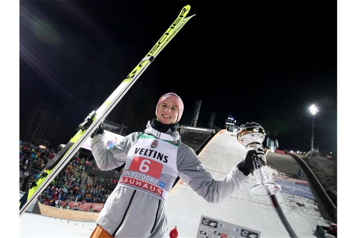 Karl Geiger jubelt mit dem silbernen Pokal für seinen zweiten Platz. Foto: Daniel Karmann/dpa