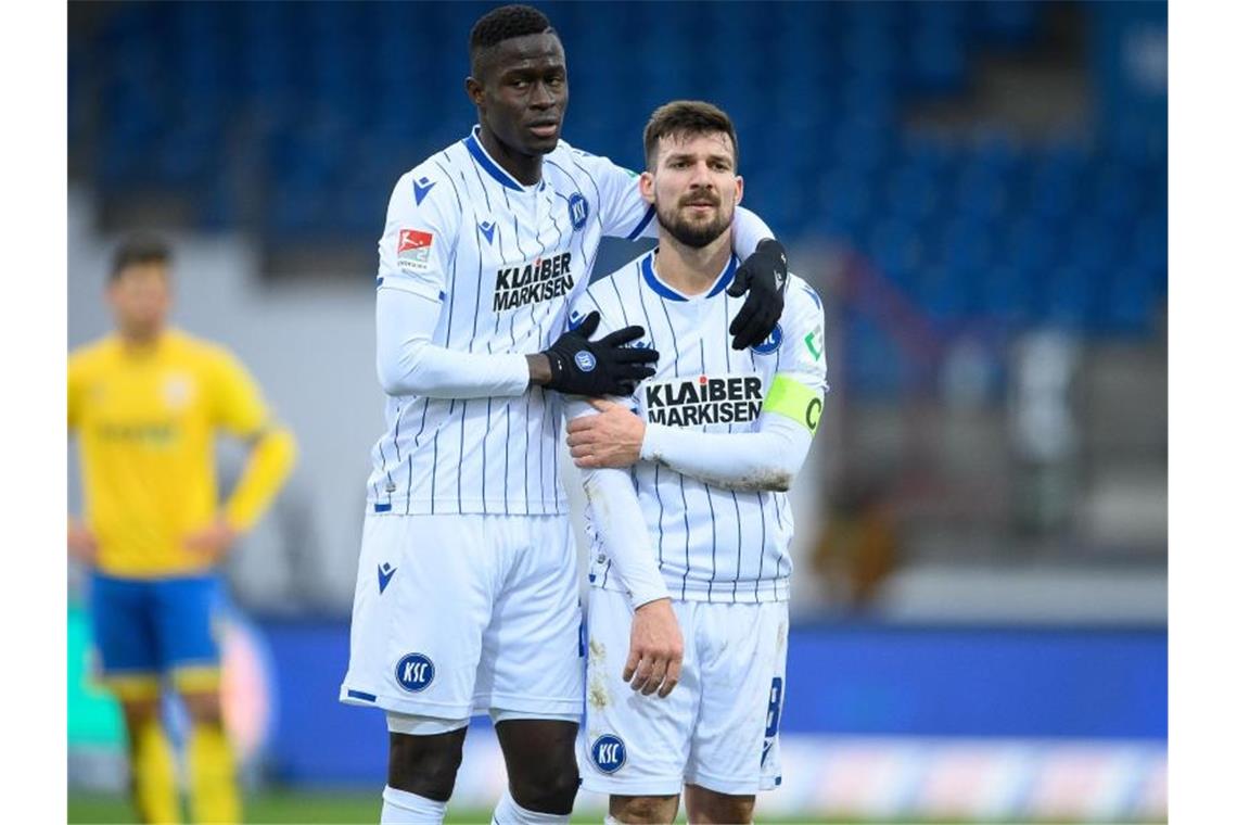 Karlsruhes Babacar Gueye (l) und Karlsruhes Jerome Gondorf umarmen sich nach dem Spiel. Foto: Swen Pförtner/dpa