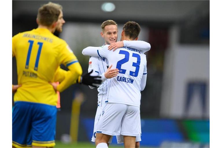 Karlsruhes Dirk Carlson (r) und Karlsruhes Christoph Kobald umarmen sich nach dem Spiel. Foto: Swen Pförtner/dpa