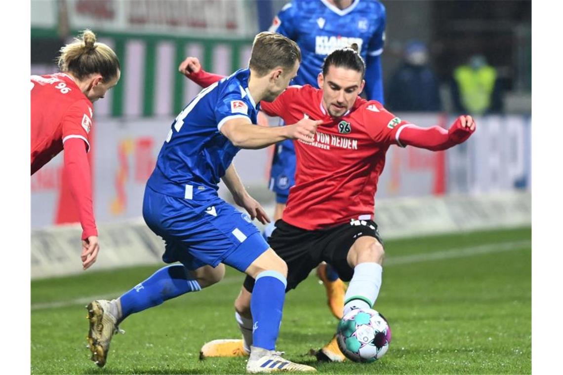 Karlsruhes Marco Thiede (l) und Valmir Sulejmani von Hannover 96 kämpfen um den Ball. Foto: Uli Deck/dpa