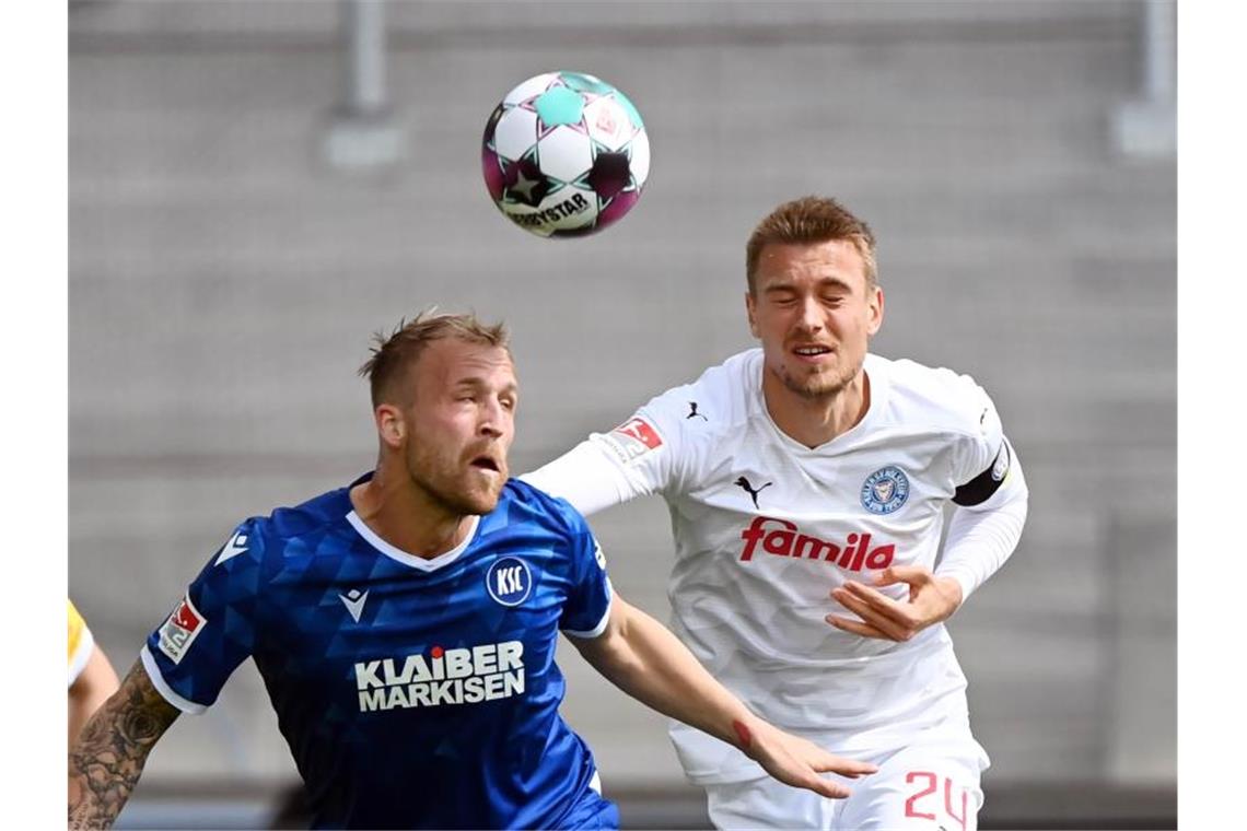 Karlsruhes Philipp Hofmann (l) im Kopfballduell mit dem Kieler Hauke Wahl. Foto: Uli Deck/dpa