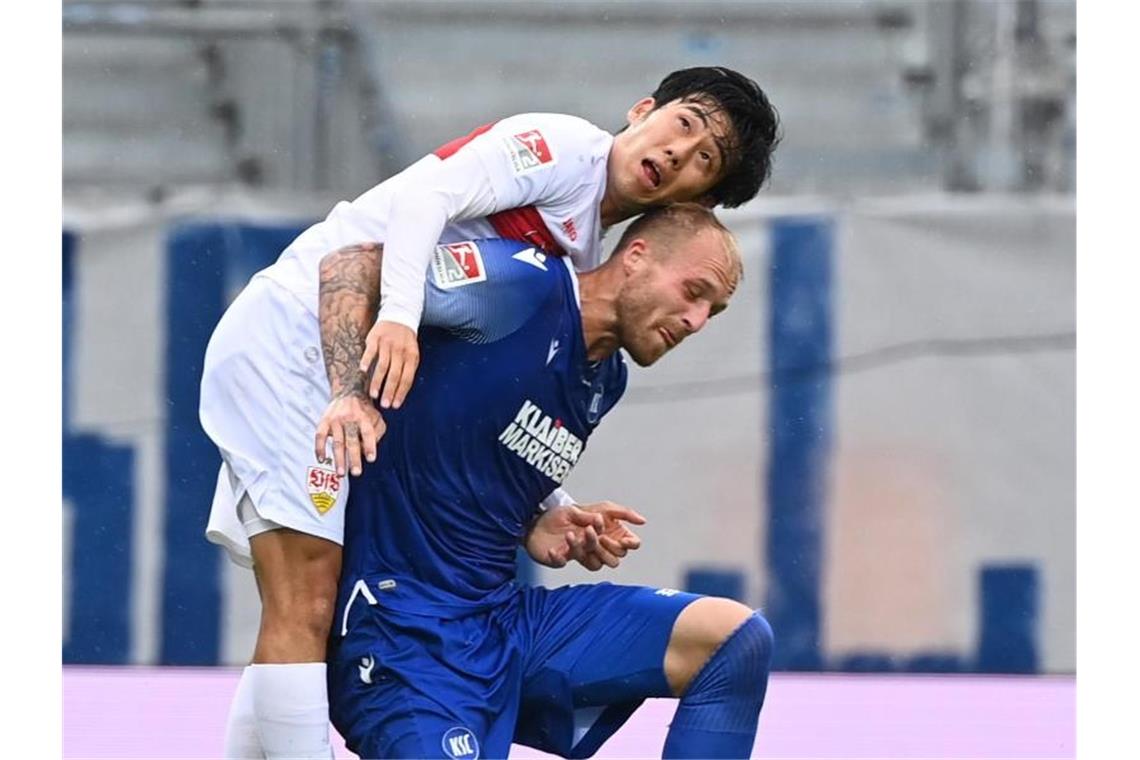 Karlsruhes Philipp Hofmann (u) und Stuttgarts Wataru Endo kämpfen um den Ball. Foto: Uli Deck/dpa-pool/dpa/Archivbild