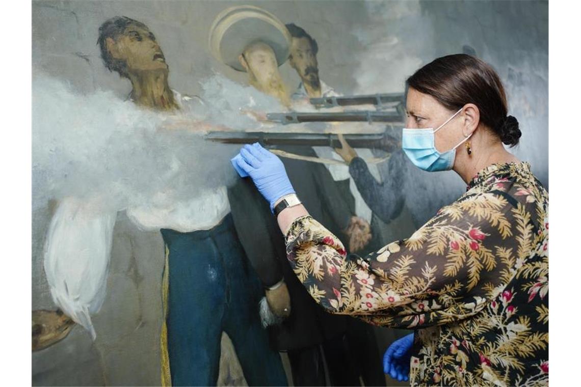 Katrin Radermacher arbeitet mit medizinischem Mundschutz und Gummihandschuhen am Gemälde. Foto: Uwe Anspach/dpa