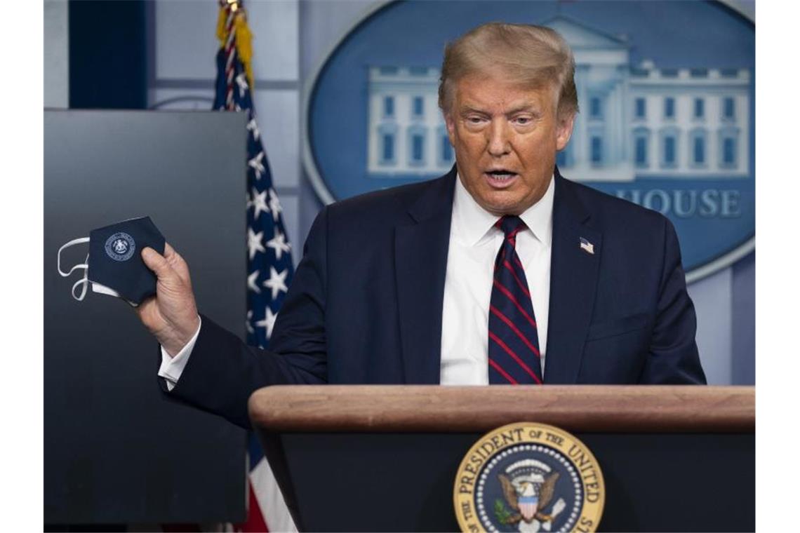 Trump schlägt in Corona-Pandemie pessimistischere Töne an Kehrtwende: US-Präsident Donald Trump präsentiert eine Schutzmaske. Foto: Evan Vucci/AP/dpa
