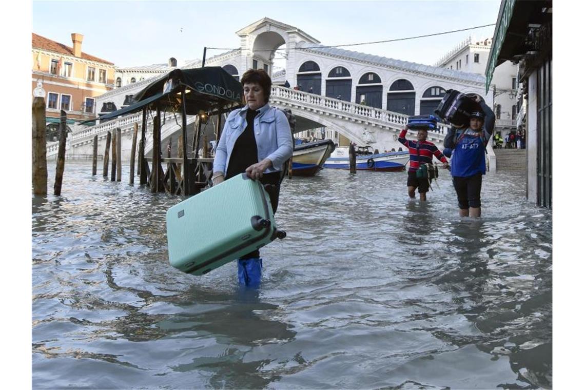 Hochwasserpegel in Venedig weiterhin hoch Kein geeigneter Ort für Rollkoffer: Touristen schleppen ihr Gepäck in der Nähe der Rialtobrücke durch eine Straße. Foto: Luigi Costantini/AP/dpa