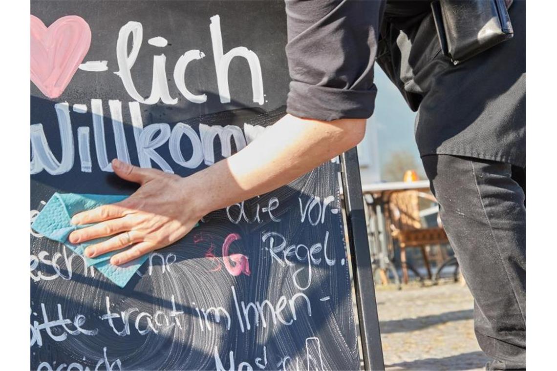 Erste bundesweite Corona-Schutzregeln fallen weg Kellner Tonet Devolli vom Restaurant Mühlstein in Wedel beseitigt die Hinweise zu den 3G-Regeln. Foto: Georg Wendt/dpa