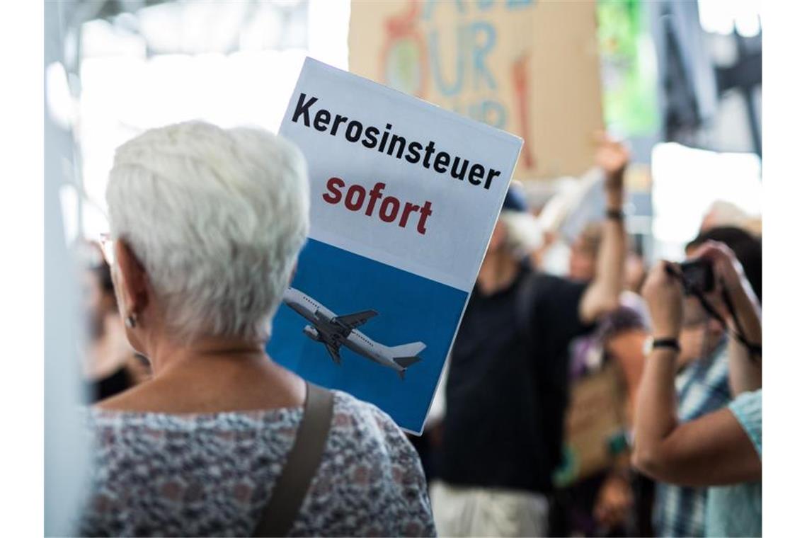 Klimaaktivisten machen Stuttgarter Flughafen unsicher „Kerosinsteuer sofort“ steht auf dem Schild einer Aktivistin. Foto: Christoph Schmidt