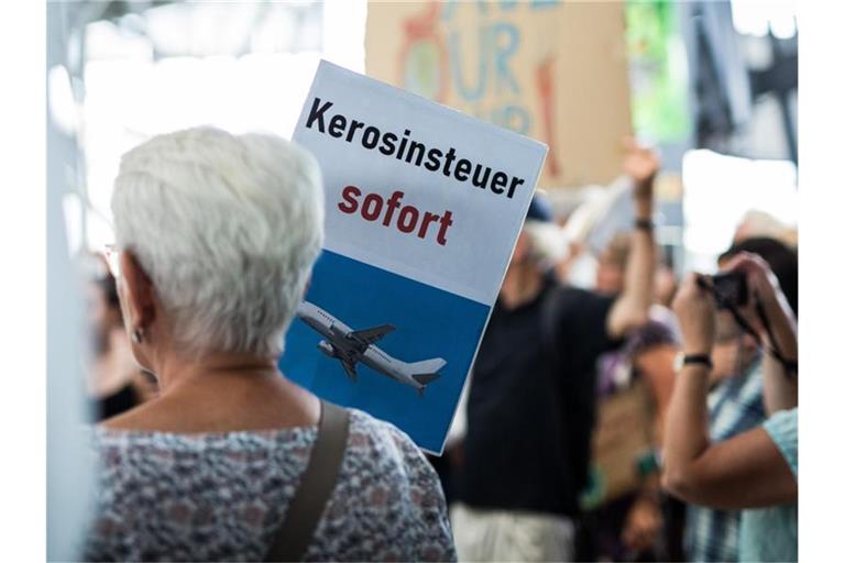 „Kerosinsteuer sofort“ steht auf dem Schild einer Aktivistin. Foto: Christoph Schmidt