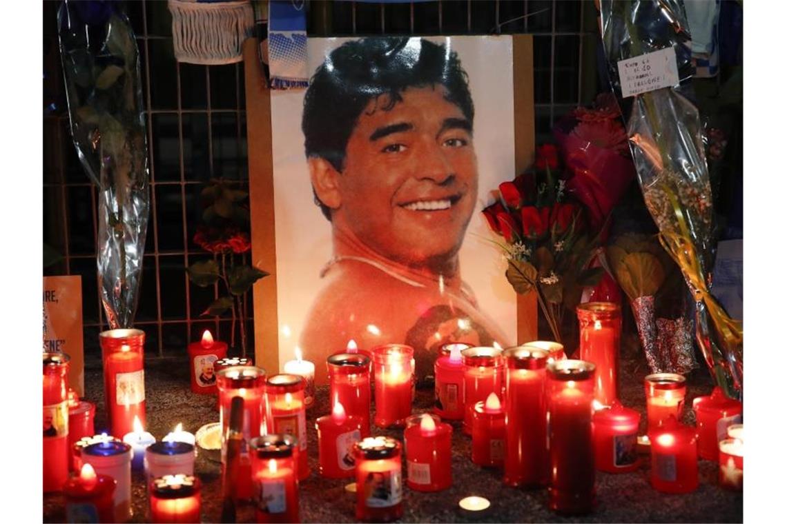 Kerzen und Blumen liegen vor dem San-Paolo-Stadion zum Gedenken an Maradona. Foto: Alessandra Tarantino/AP/dpa
