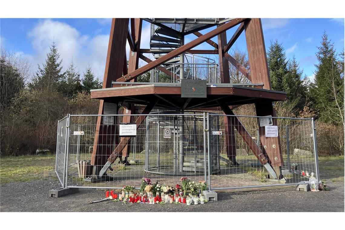 Unter dem Aussichtsturm brennen Kerzen der Trauer Kerzen und Blumen vor dem Absperrgitter.