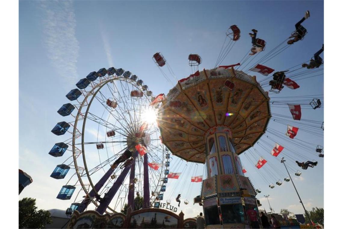 Kettenkarussell und Riesenrad drehen sich auf der Cannstatter Wasen. Foto: Franziska Kraufmann/dpa/Archivbild