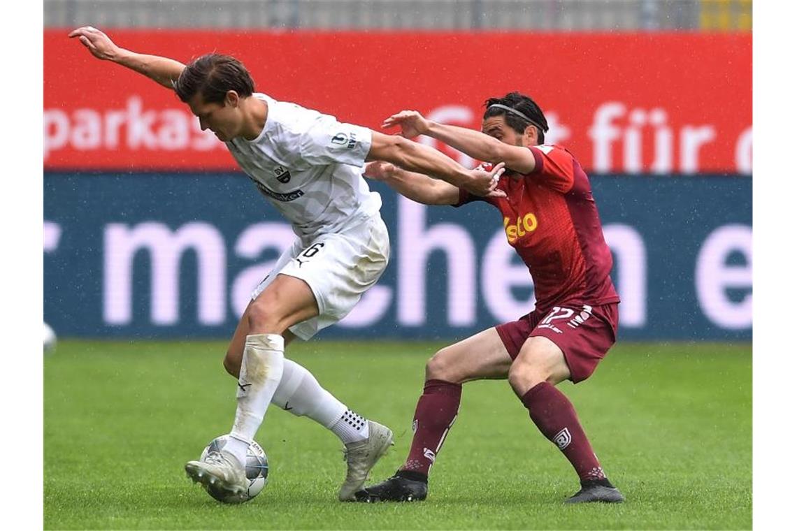 Kevin Behrens (l) vom SV Sandhausen im Zweikampf mit dem Regensburger Oliver Hein. Foto: Alexander Scheuber/Getty Images Europe/Pool/dpa