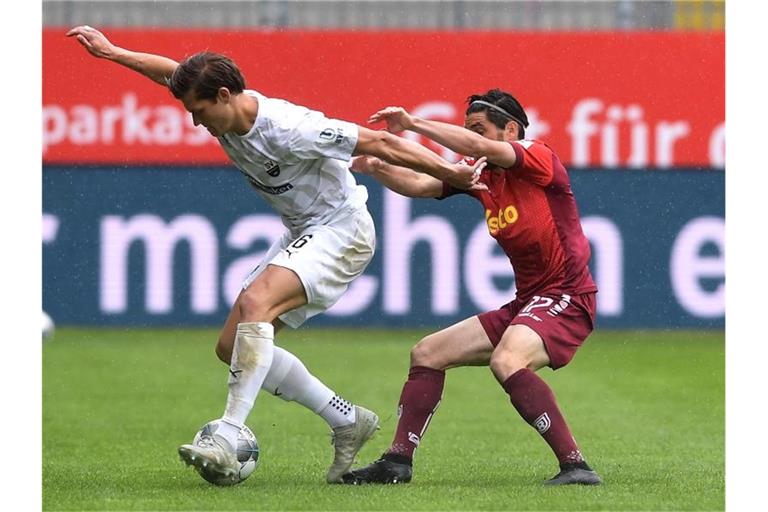 Kevin Behrens vom SV Sandhausen und Oliver Hein von Jahn Regensburg (l-r.) im Zweikampf um den Ball. Foto: Alexander Scheuber/Getty Images Europe/Pool/dpa