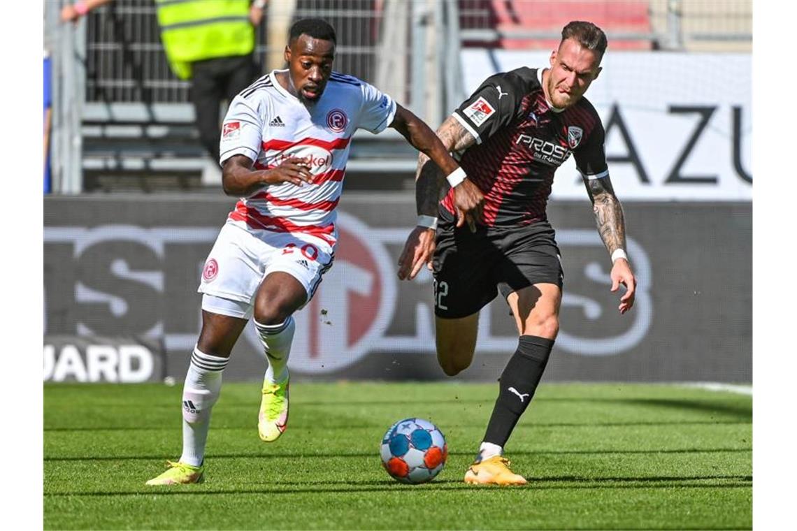 Khaled Narey von Düsseldorf (l) und Patrick Schmidt vom FC Ingolstadt jagen dem Ball hinterher. Foto: Armin Weigel/dpa