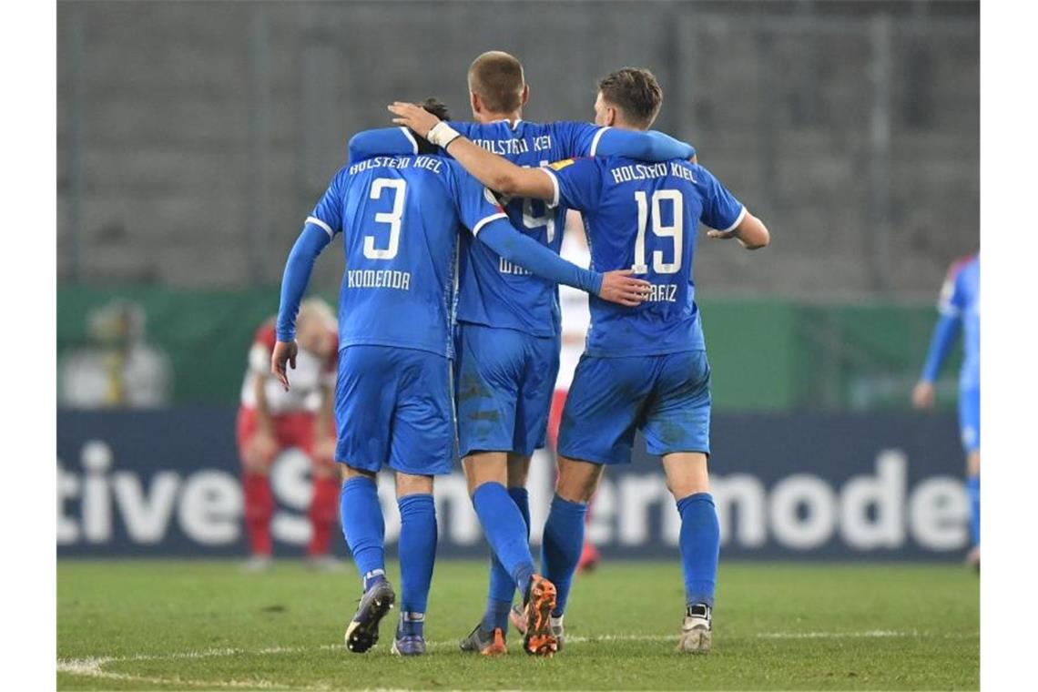 Kieler Helden feiern den Einzug ins DFB-Pokal-Halbfinale auf dem Platz - und später auch im Bus. Foto: Martin Meissner/AP POOL/dpa