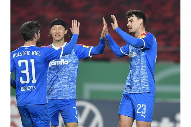 Kiels Janni Luca Serra (r) bejubelt sein Tor mit Fin Bartels (l) und Jae-Sung Lee. Foto: Martin Meissner/AP POOL/dpa
