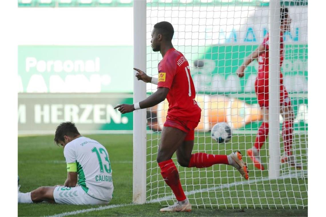 Zweitliga-Spitzenreiter Stuttgart setzt sich ab Kiels Makana Baku (M) jubelt über seinen Treffer zum 2:0 neben Marco Caligiuri (l) von der SpVgg Greuther Fürth. Foto: Daniel Karmann