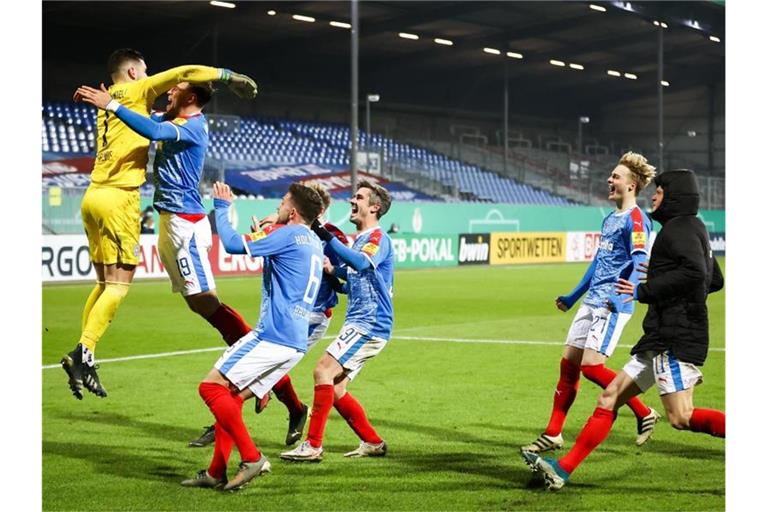 Kiels Torwart Ioannis Gelios (l) und seine Mitspieler feiern ihren Sieg mit 7:6 nach Elfmeterschießen. Foto: Christian Charisius/dpa