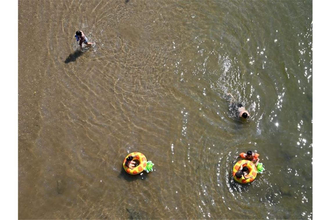 Kinder baden bei einer Temperatur von weit über 30 Grad an einer flachen Stelle des Rheins in Köln. Foto: Henning Kaiser/dpa