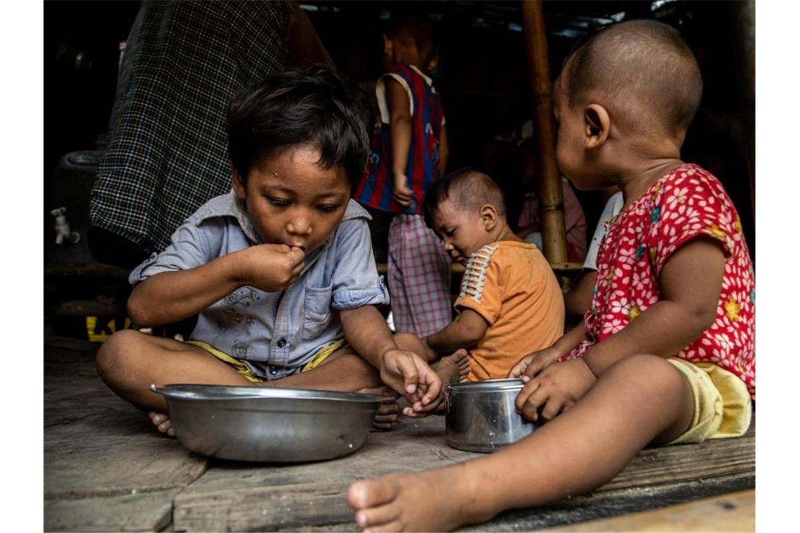 Kinder einer vom World Food-Programme unterstützten Familie sitzen beim Mittagessen in ihrer Hütte im Hlaing Thar Yar Township. (Archivbild). Foto: Kaung Htet Lin/World Food Programme/dpa