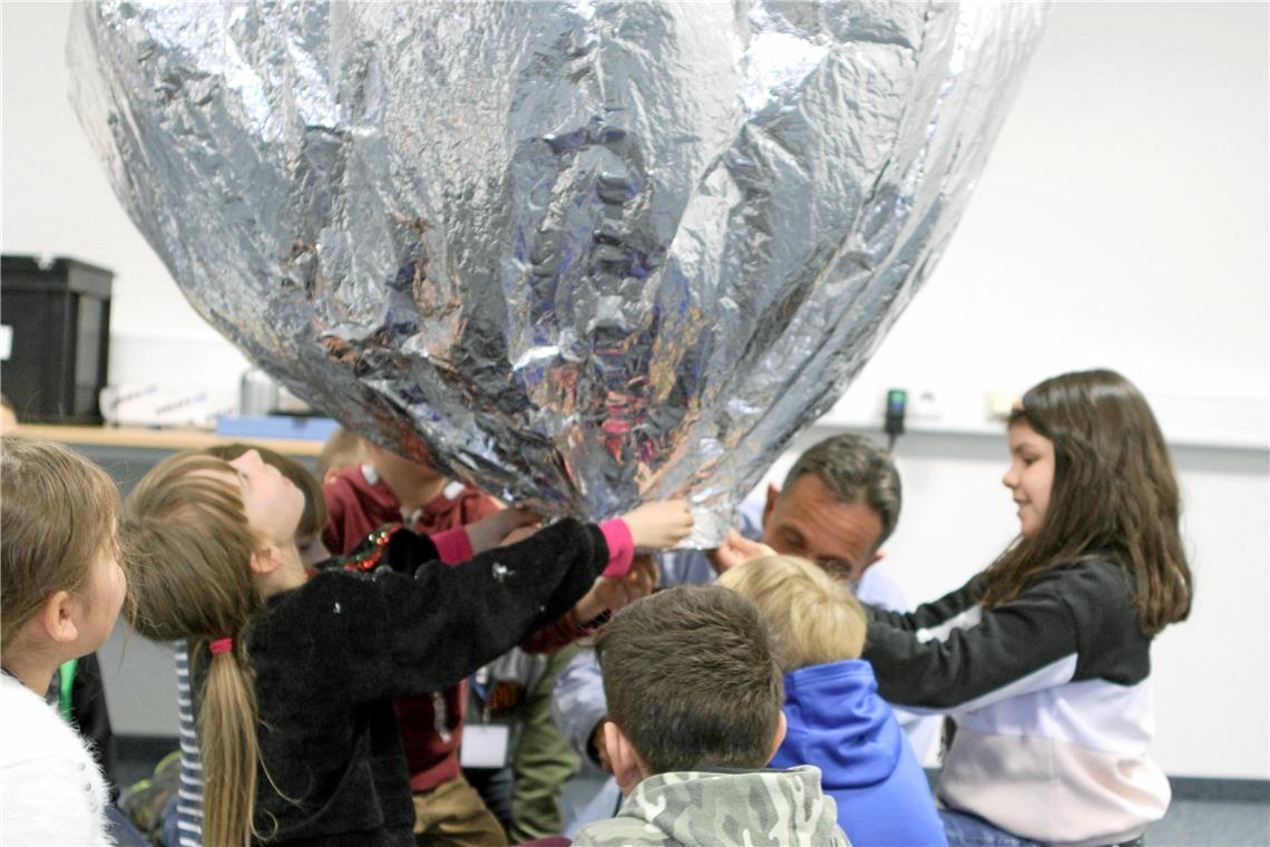 Kinder experimentieren: Im Vortragsraum wird ein Ballon mit Helium gefüllt. Dann dürfen ihn die Jungforscher steigen lassen. Foto: J. Denia