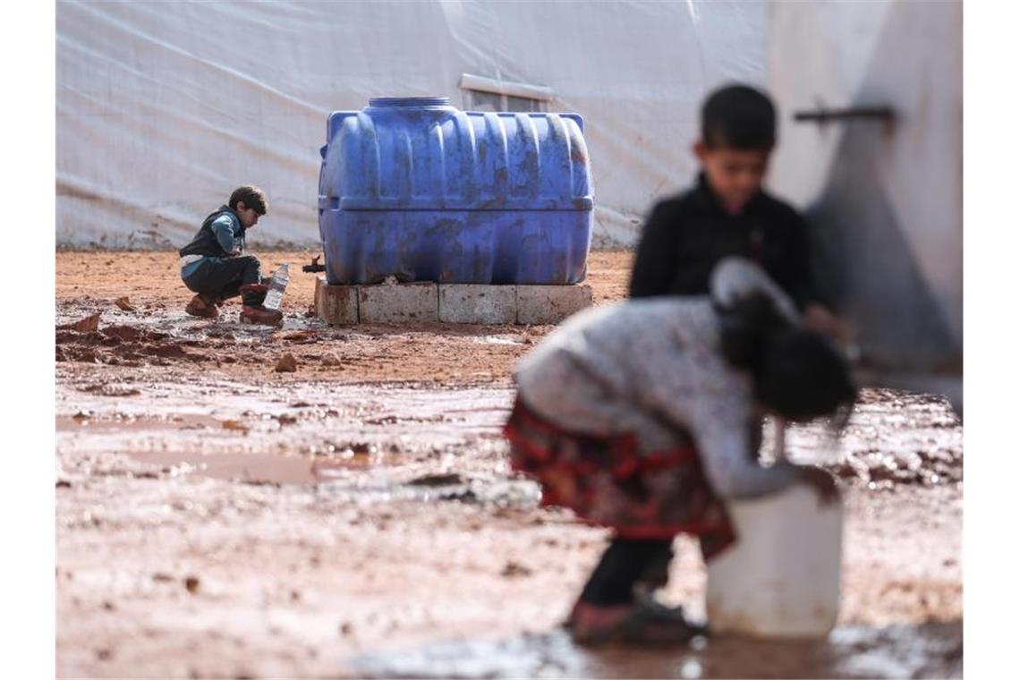 Kinder füllen in einem provisorischen Lager in der Region Idlib Behälter mit Wasser auf. Von den Hilfsgütern, die bisher die Grenzübergänge passierten, sind westlichen Angaben zufolge etwa 2,8 Millionen Menschen abhängig. Foto: Anas Alkharboutli/dpa