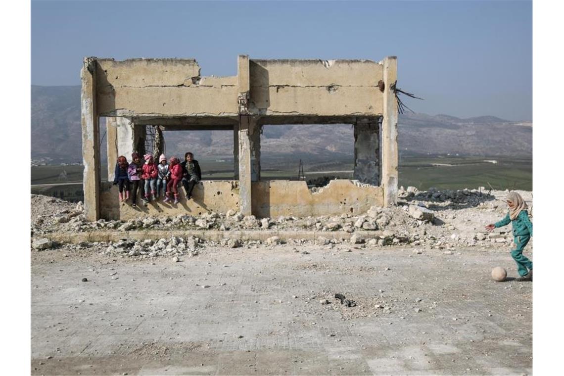 Kinder spielen in den Trümmern einer zerstörten Schule. Foto: Anas Alkharboutli/dpa