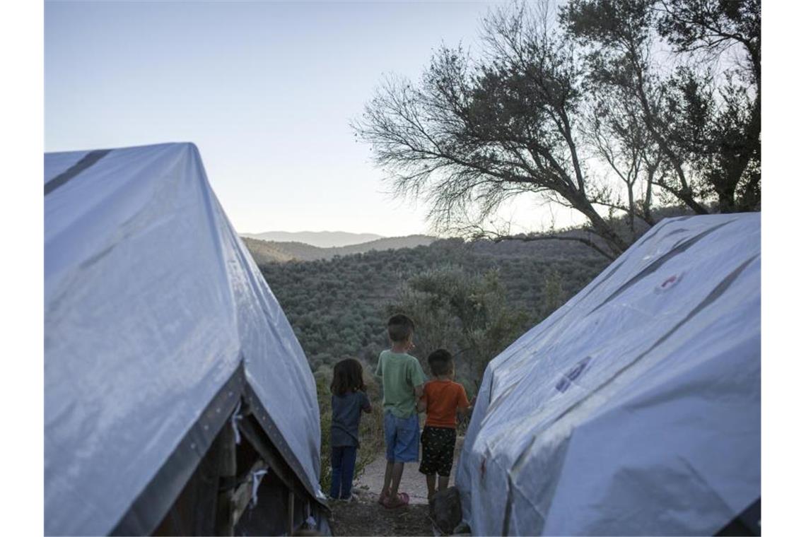 Kinder stehen zwischen Zelten in einem provisorischen Flüchtlingslager auf Lesbos. Foto: Socrates Baltagiannis/dpa