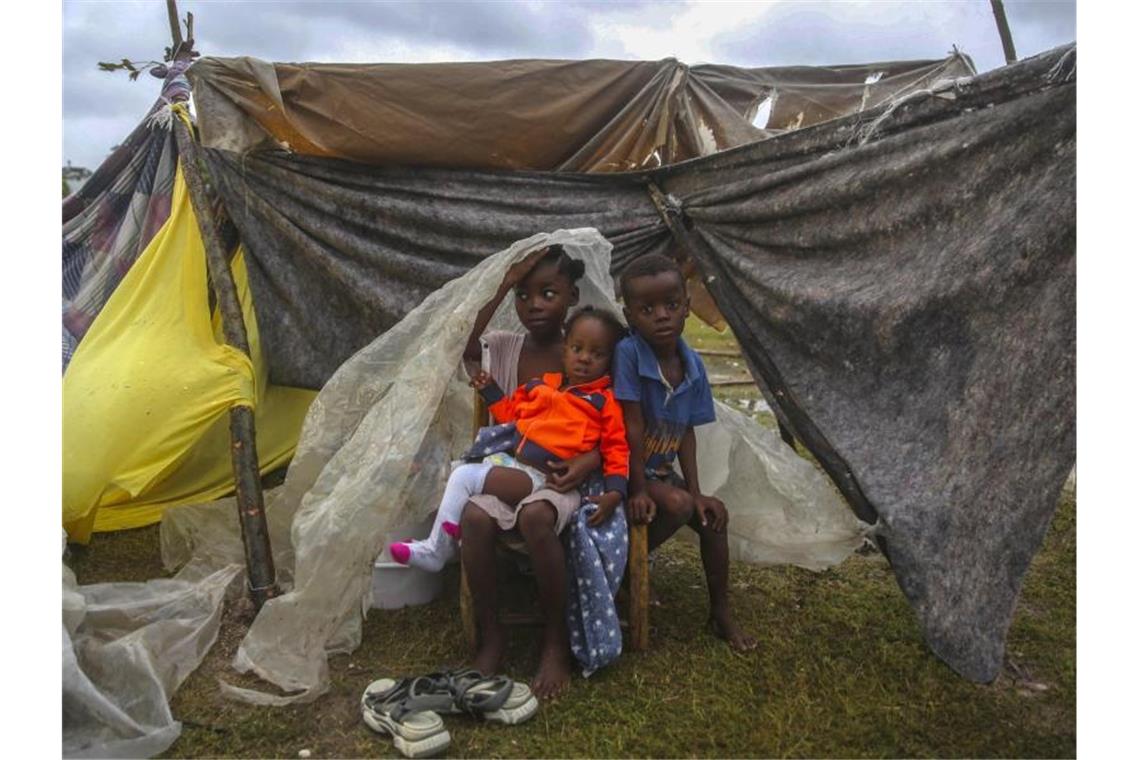 Kinder versuchen in Les Cayes, sich mit einer Plane vor dem Regen zu schützen. Foto: Joseph Odelyn/AP/dpa