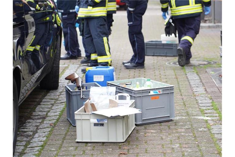 Kisten stehen neben einem Auto und der Polizei zugehörigen Personen auf einem Gehweg. Foto: Benedikt Spether/dpa/Archivbild