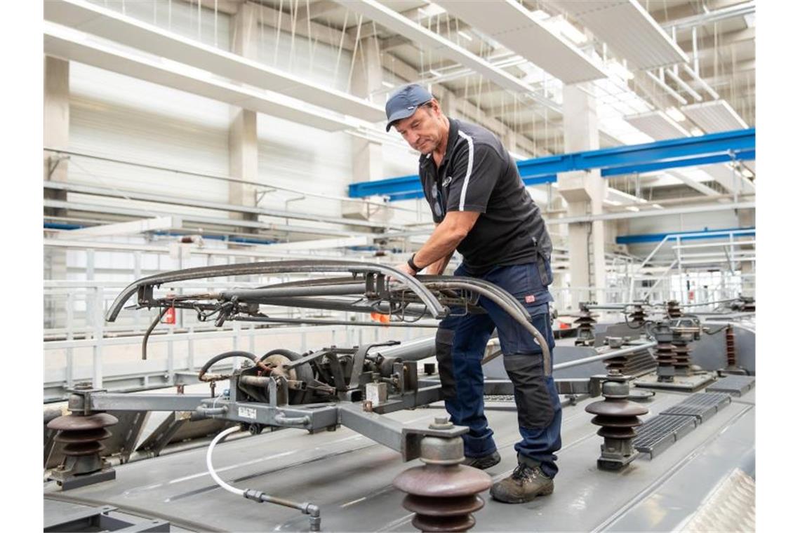 Klaus David, Elektriker in Rente bei der Deutschen Bahn, prüft auf einer Lokomotive im Nürnberger Bahnwerk den Stromabnehmer. Foto: Daniel Karman