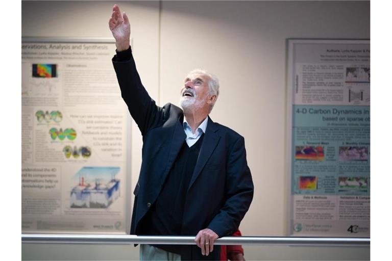 Klaus Hasselmann winkt im Max-Planck-Institut für Meteorologie in Hamburg jubelnden Mitarbeitenden zu. Foto: Daniel Reinhardt/dpa