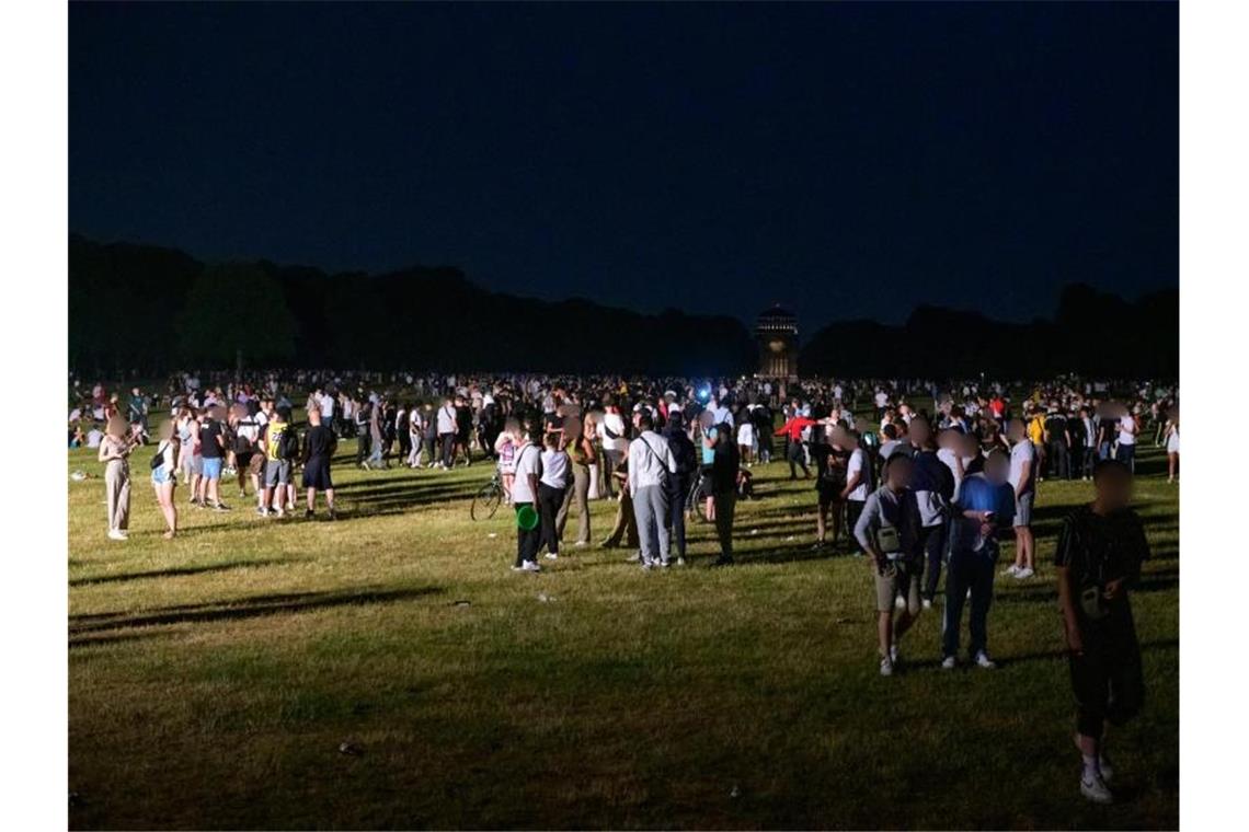 Kleinere und größere Gruppen stehen im Hamburger Stadtpark im Schein eines Polizeischeinwerfers. Foto: Jonas Walzberg/dpa