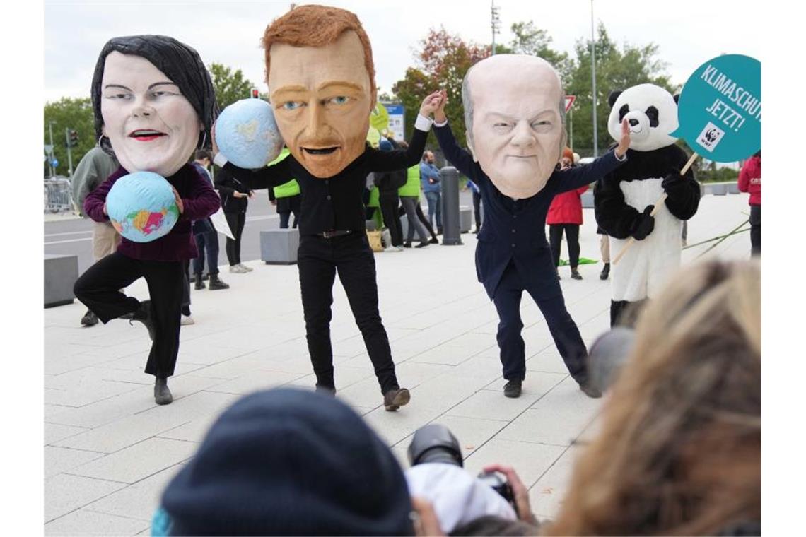Klimaschutzaktivisten protestieren mit Masken, die Annalena Baerbock, Christian Lindner und Olaf Scholz darstellen sollen. Foto: Kay Nietfeld/dpa