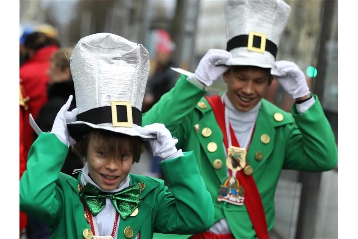 Kölner Karnevalisten halten im Wind ihre Kostüme fest. Foto: Oliver Berg/dpa